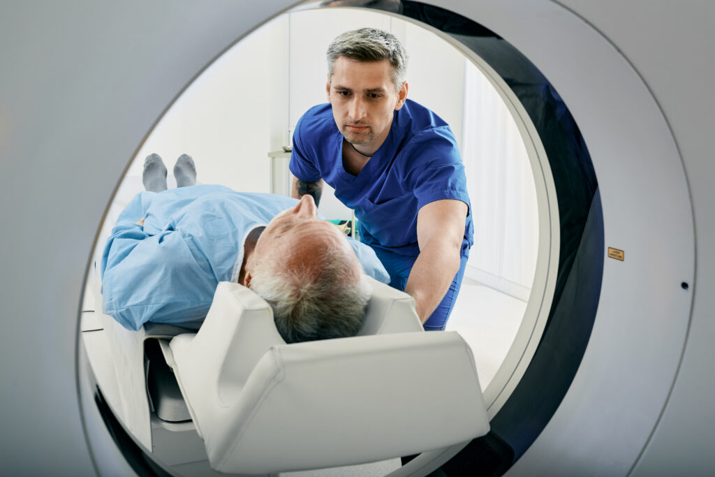 Senior man going into CT scanner. CT scan technologist overlooking patient in Computed Tomography scanner during preparation for procedure