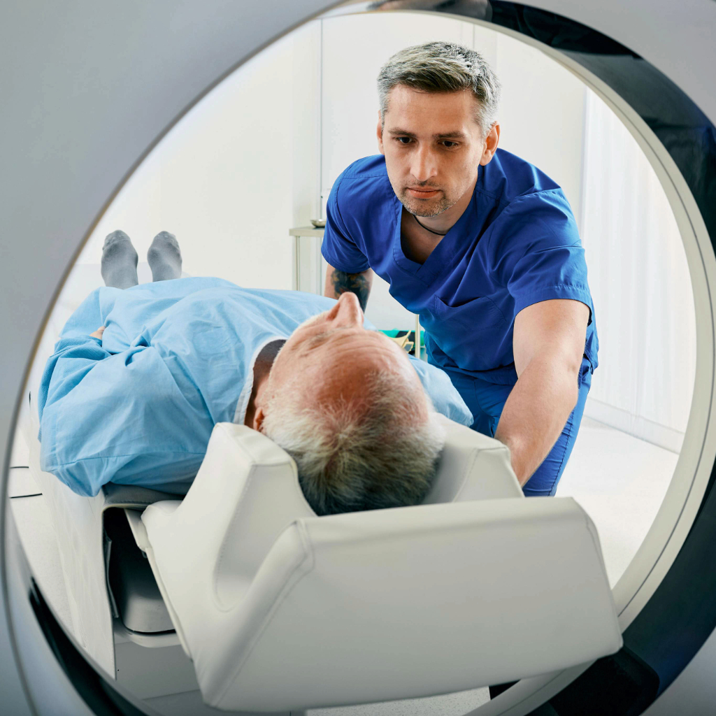 Senior man going into CT scanner. CT scan technologist overlooking patient in Computed Tomography scanner during preparation for procedure